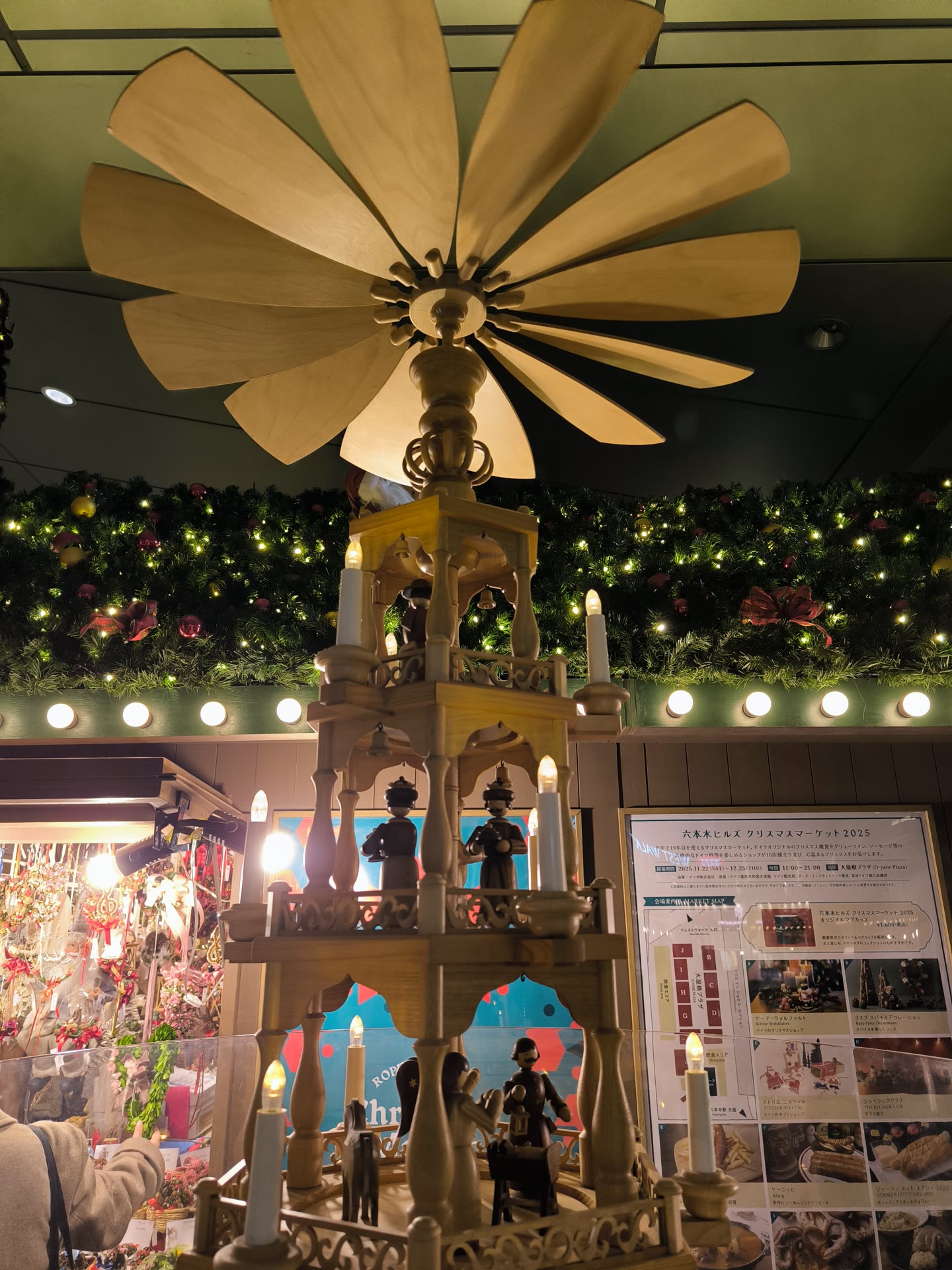 ปิรามิดไม้คริสต์มาสประดับโคมไฟ พร้อมป้ายข้อมูลงาน Roppongi Hills Christmas Market 2025 (ภาพปี 2568)
